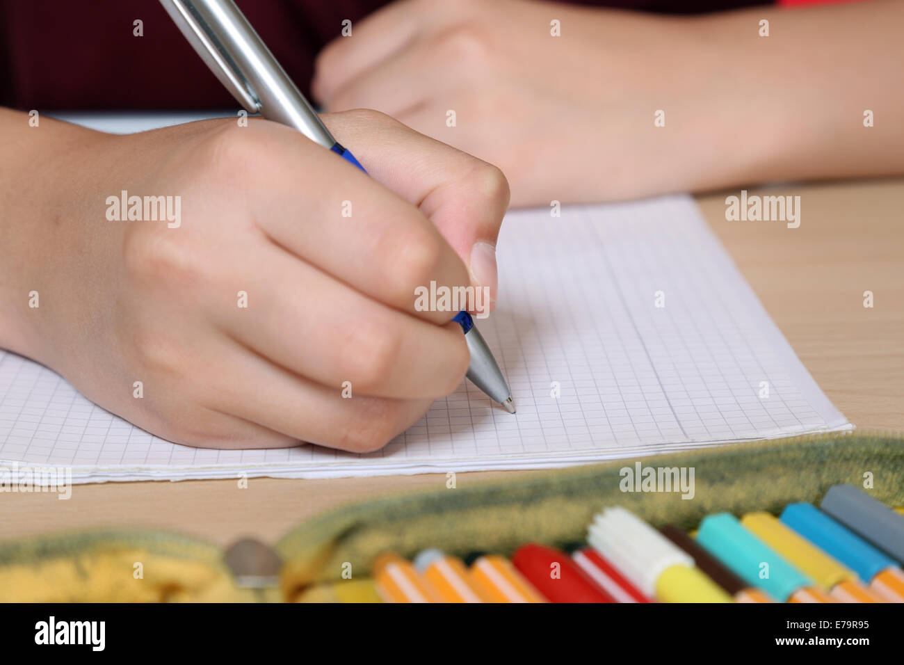 Giovane studente iscritto nel suo quaderno a scuola Foto Stock