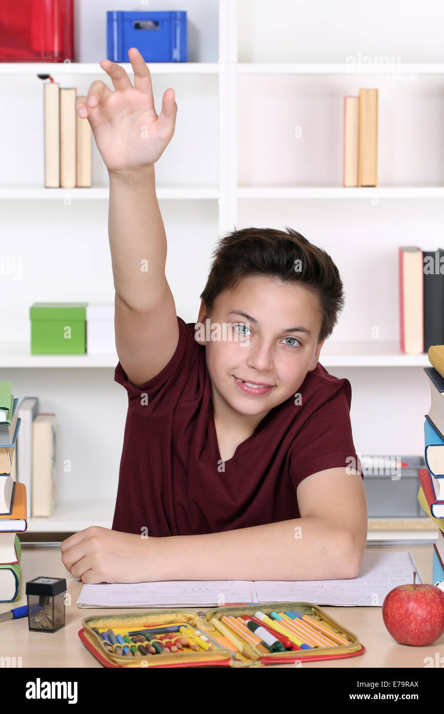 Un giovane ragazzo adolescente con mano sollevata a scuola Foto Stock