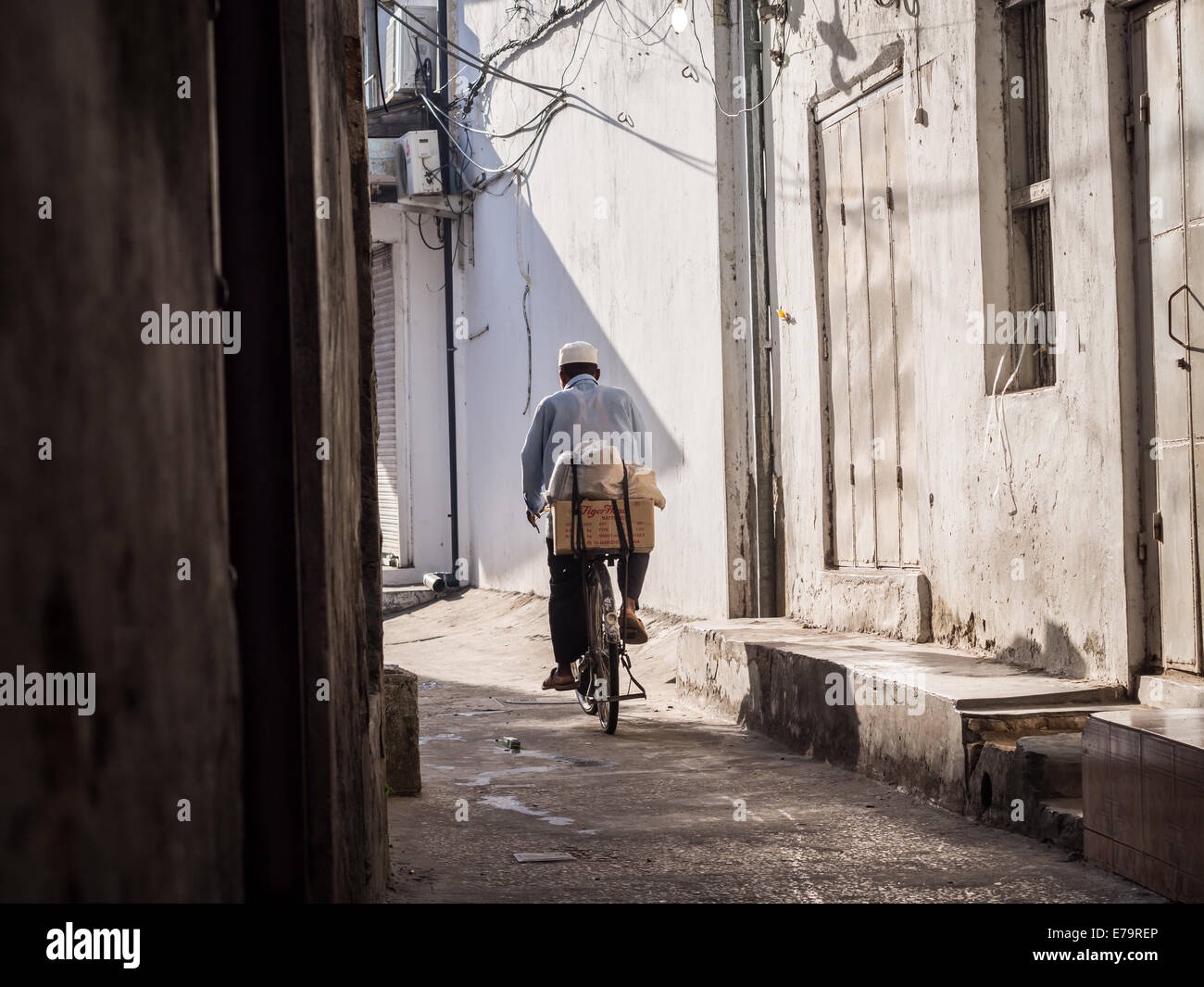 L'uomo mountain bike su una delle strade di Stone Town, la capitale di Zanzibar. Foto Stock