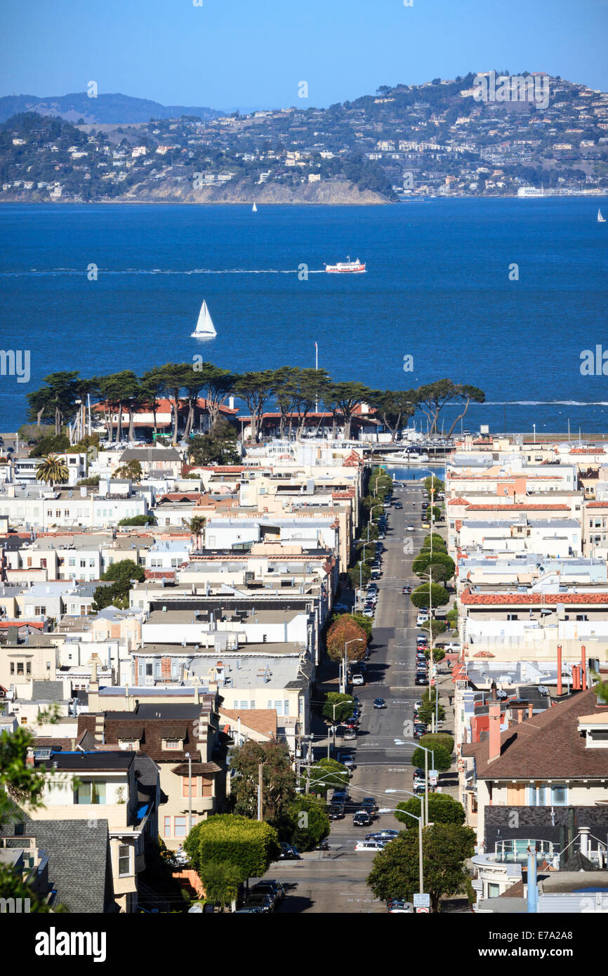 Guarda case lungo Broderick Street nel quartiere Marina di San Francisco con la città in collina di fronte alla baia Foto Stock