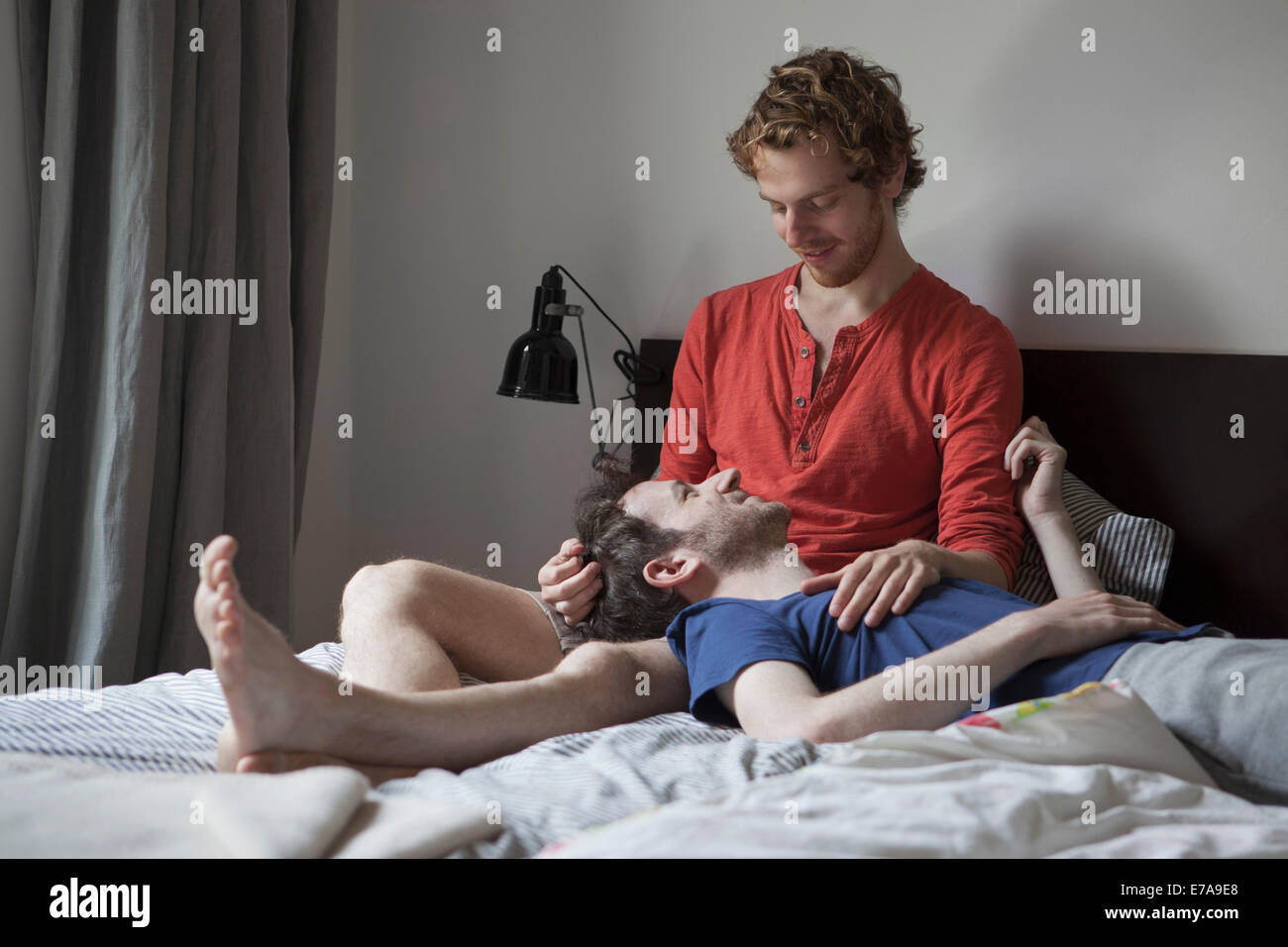 Amorevole coppia gay guardando ogni mentre vi rilassate nel letto di casa Foto Stock