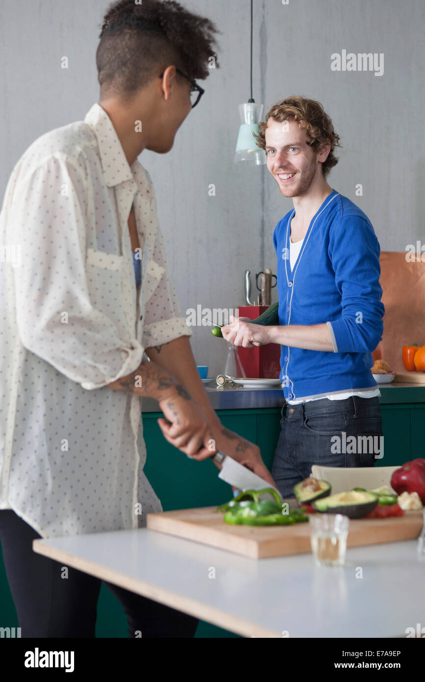 Uomo sorridente preparare il cibo con la femmina amico in cucina Foto Stock