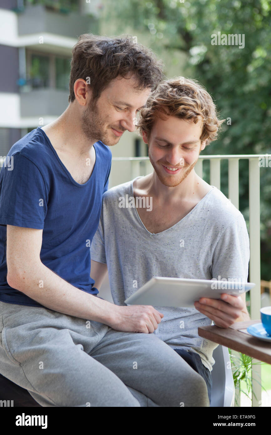 Coppia gay con tavoletta digitale al portico Foto Stock