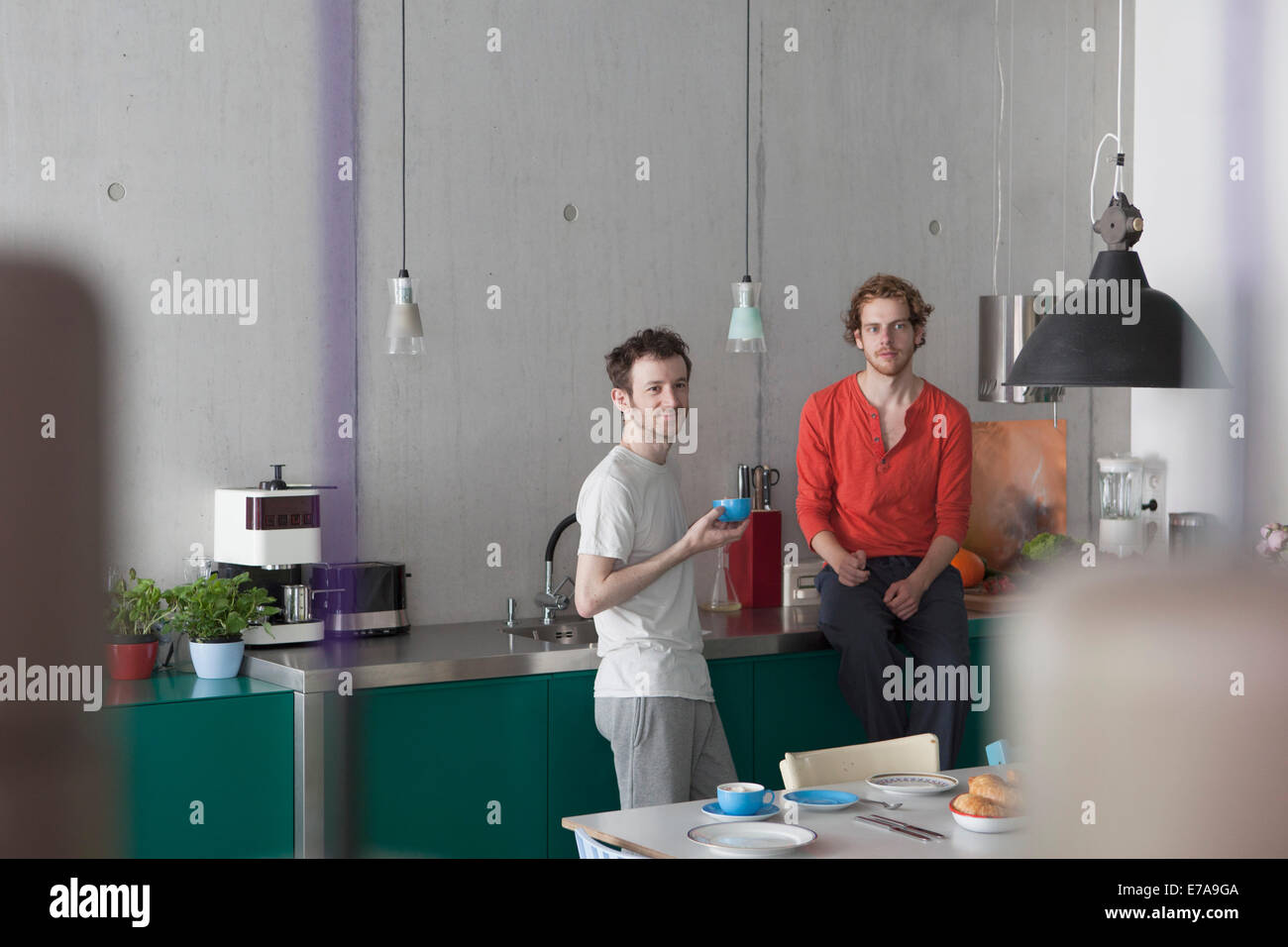 Giovane coppia gay che guarda lontano in cucina Foto Stock