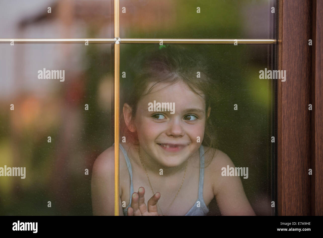 Close-up di una ragazza che guarda fuori attraverso la finestra Foto Stock