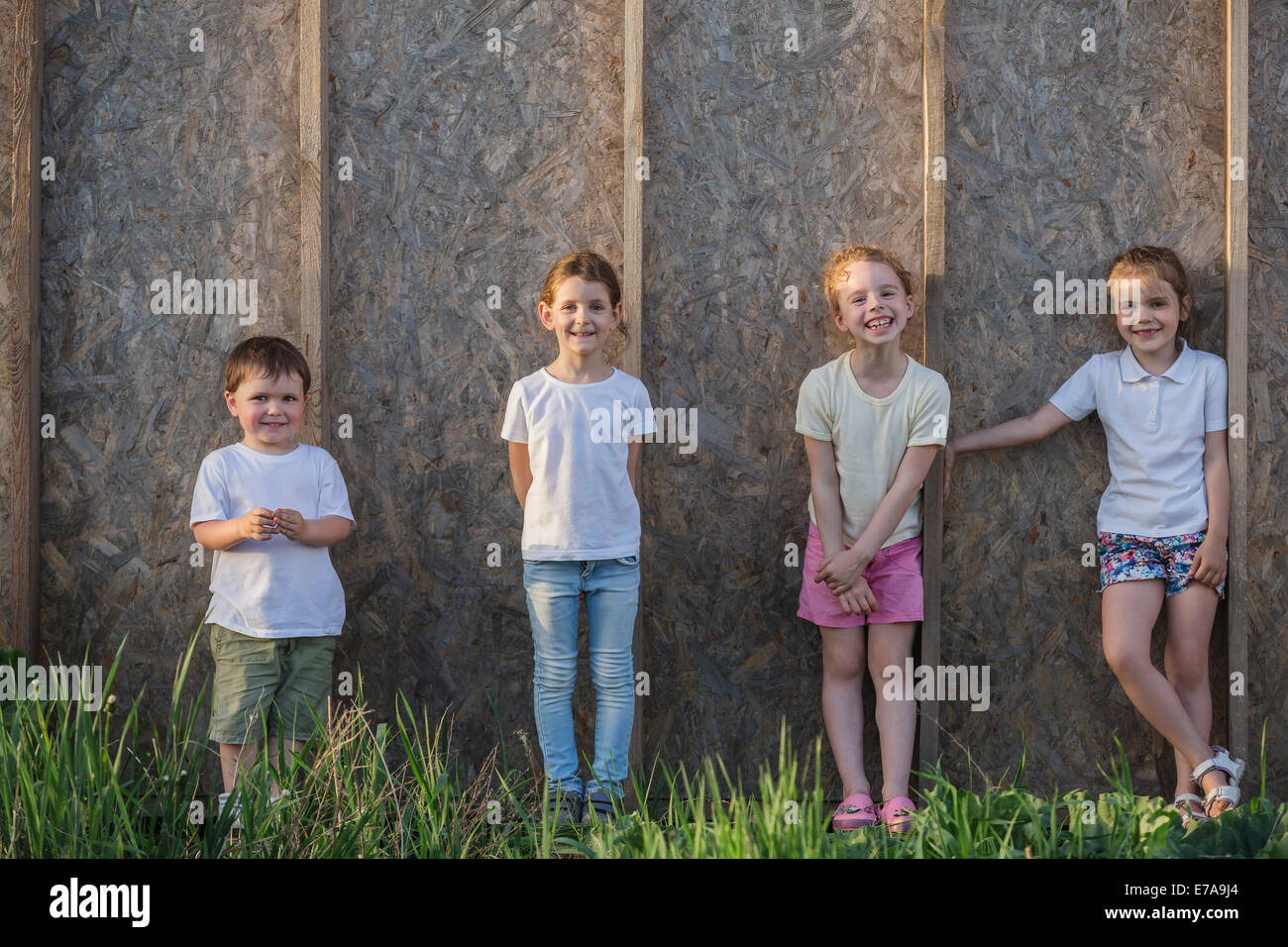 Ritratto di adorabili bambini in piedi contro la parete in legno Foto Stock