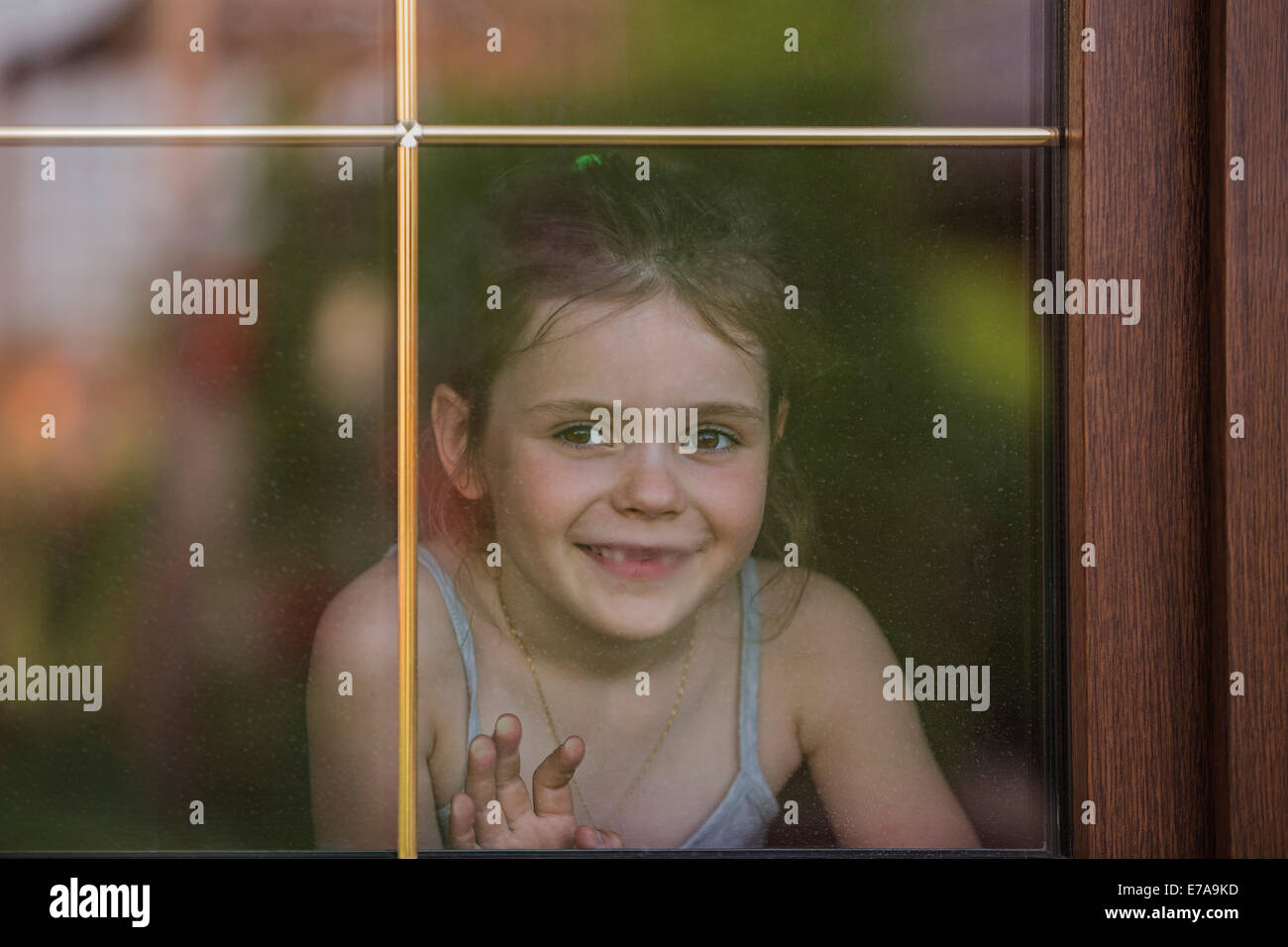 Felice bambina guardando fuori attraverso la finestra Foto Stock