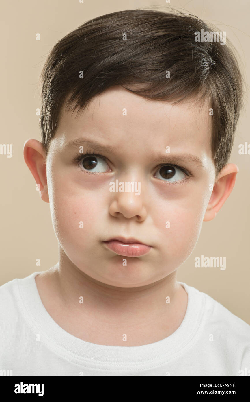 Close-up di ragazzo serio contro sfondo beige Foto Stock