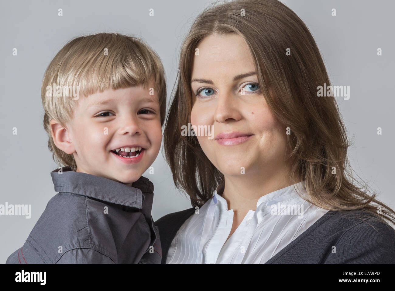 Ritratto di il figlio e la madre sorridente contro uno sfondo grigio Foto Stock