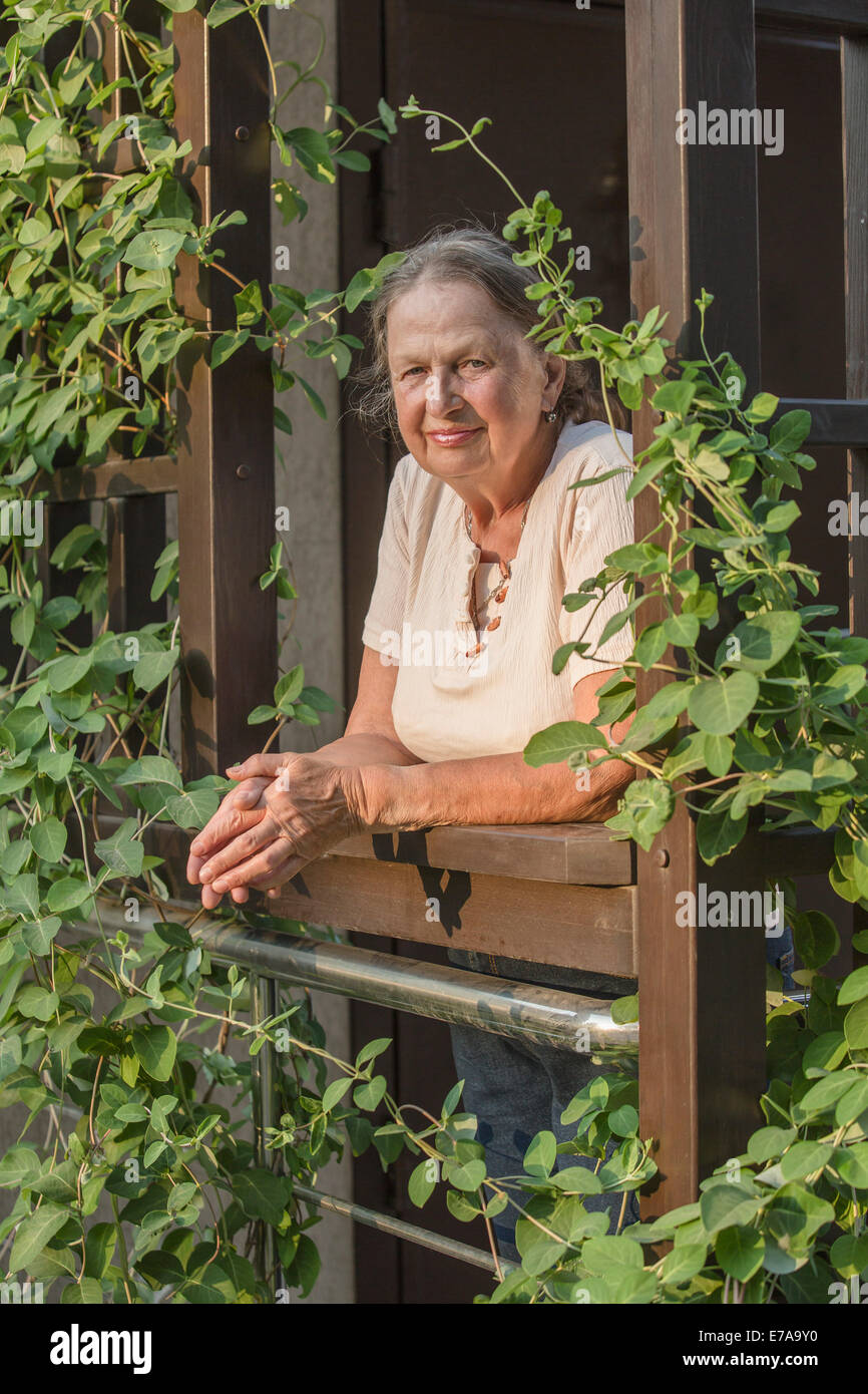 Ritratto di donna senior con le mani incrociate al balcone Foto Stock