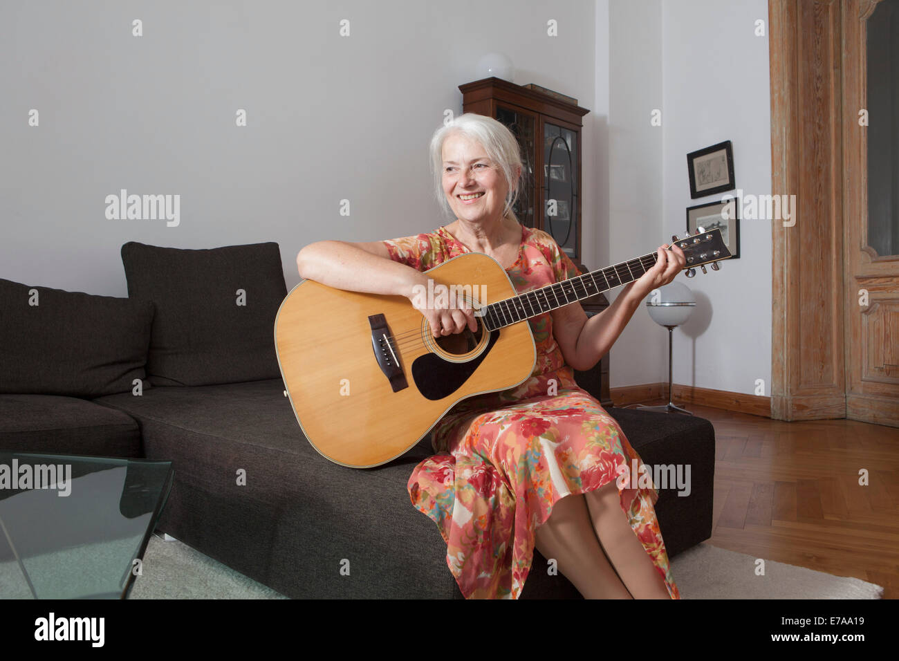 Le donne anziane a suonare la chitarra nel salotto di casa Foto Stock