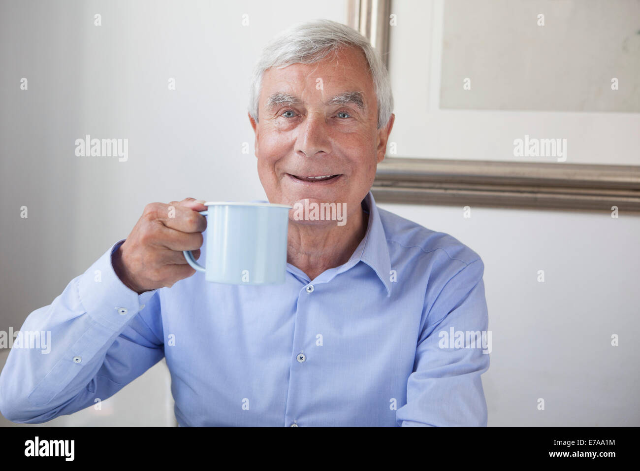 Ritratto di felice uomo senior holding tazza da caffè a casa Foto Stock