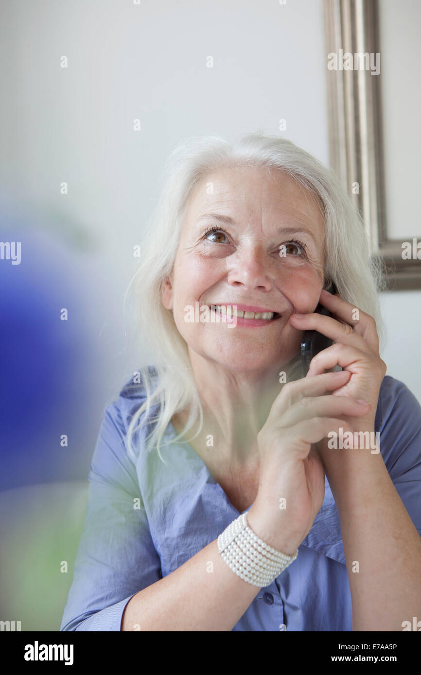 Felice senior donna rispondendo telefono mobile a casa Foto Stock