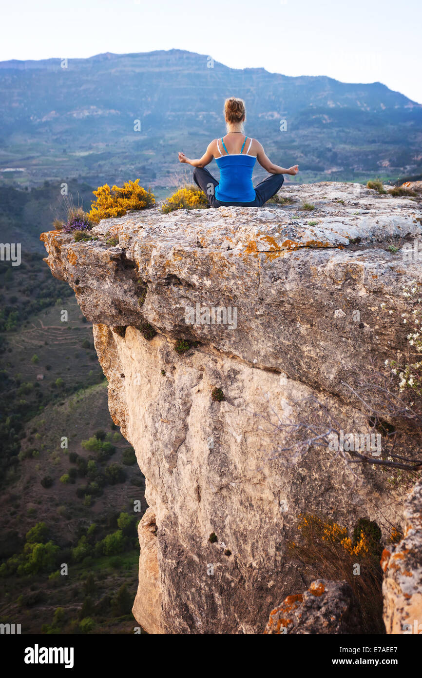 Giovane donna seduta su una roccia e gode di vista valle Foto Stock