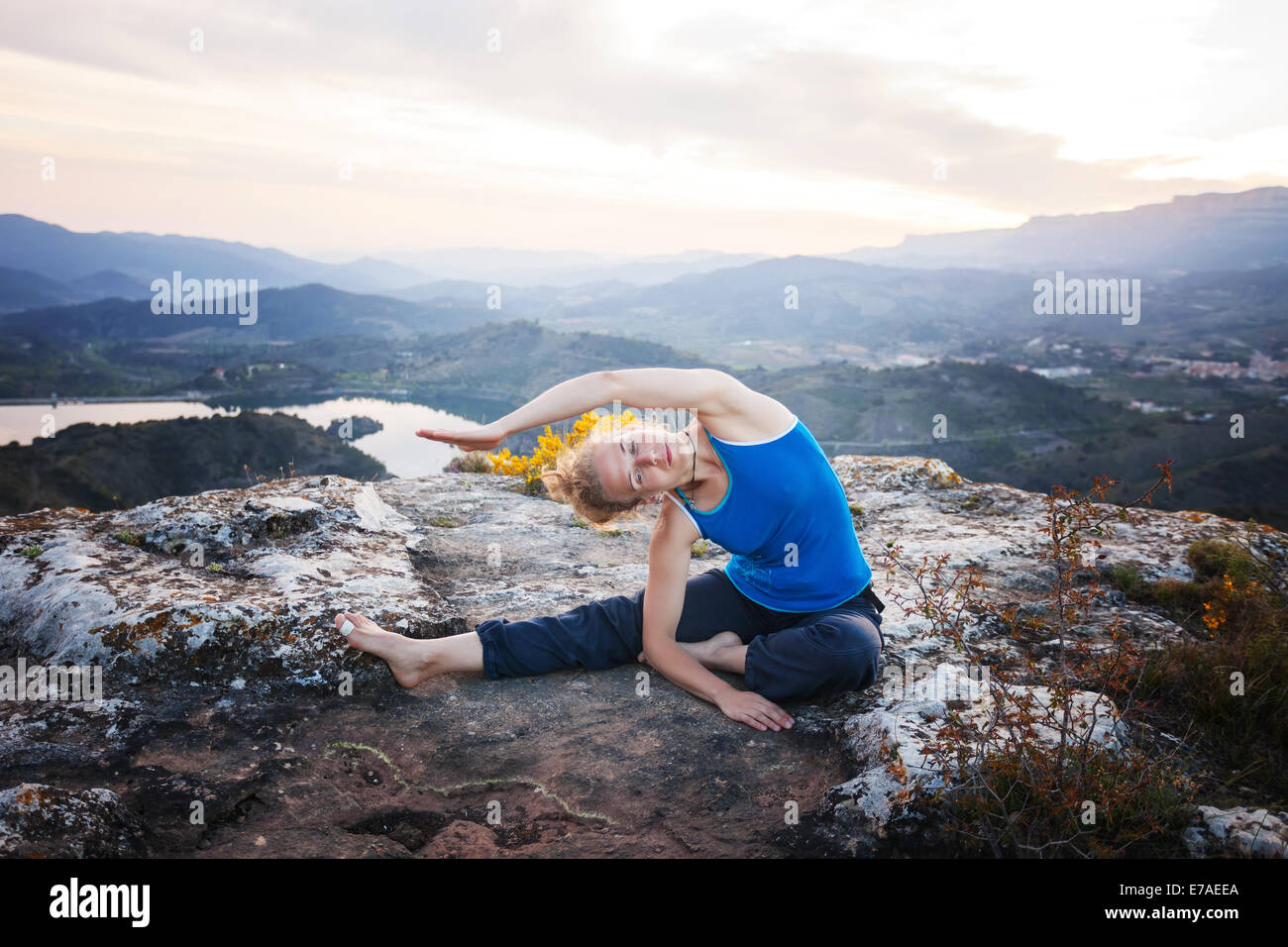 Giovane donna caucasica lavoro su una roccia contro vista valle Foto Stock