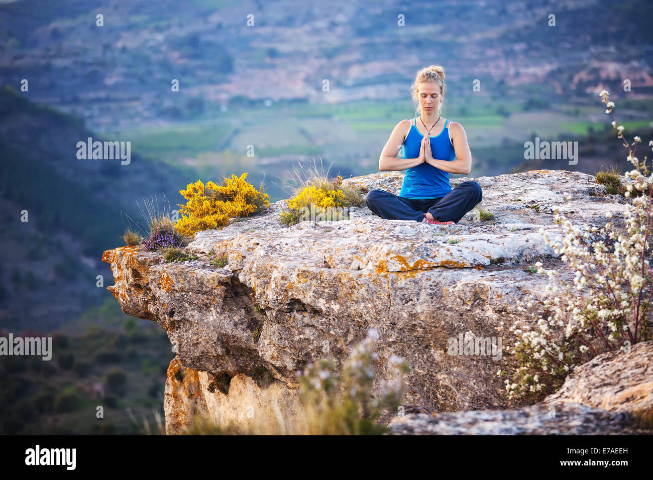 Giovane donna seduta su una roccia e godersi la vista della valle. La ragazza si siede nella posizione asana Foto Stock