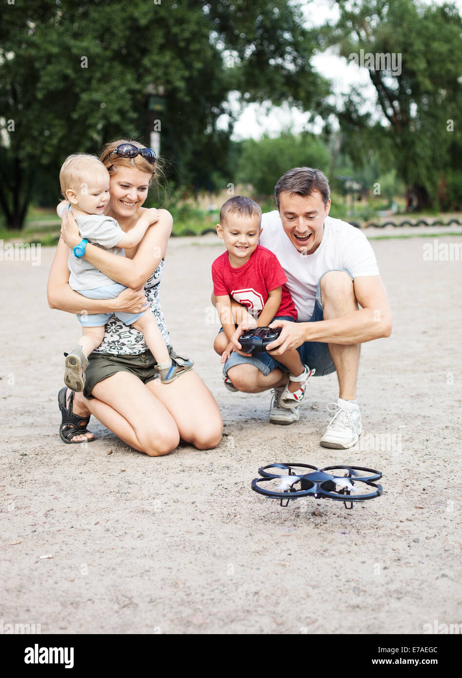 Famiglia giovane con due ragazzi giocare con RC quadrocopter toy Foto Stock