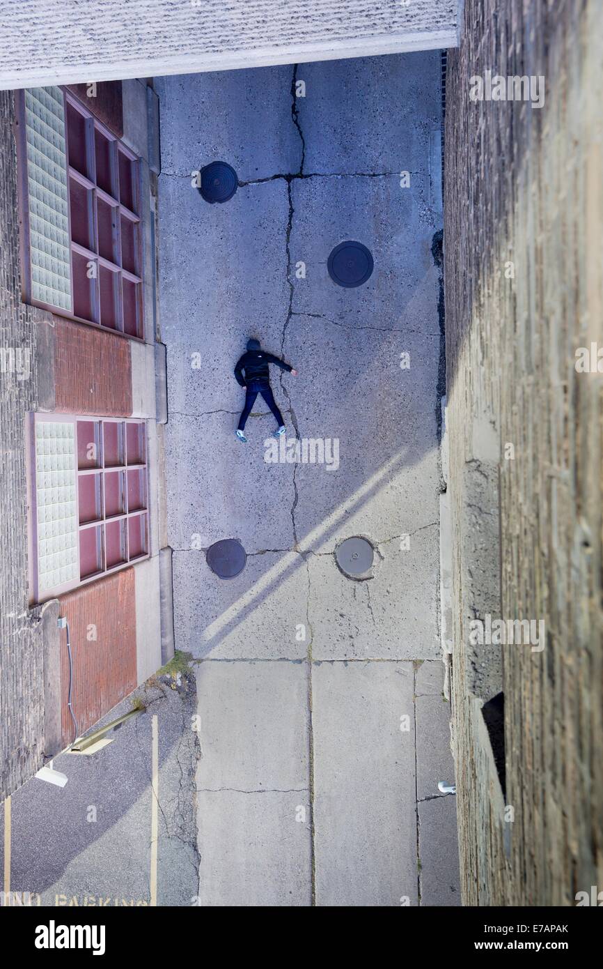 Una persona incosciente sdraiato a faccia in giù in un vicolo urbano Foto Stock