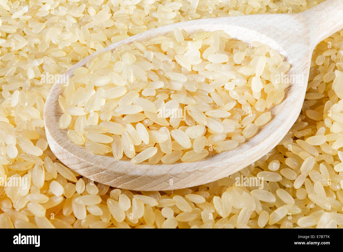Vista dettagliata del cucchiaio di legno sul pieno di sfondo di riso Foto Stock