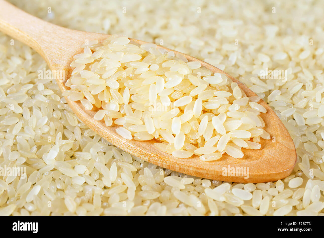 Vista dettagliata del cucchiaio di legno sul pieno di sfondo di riso Foto Stock