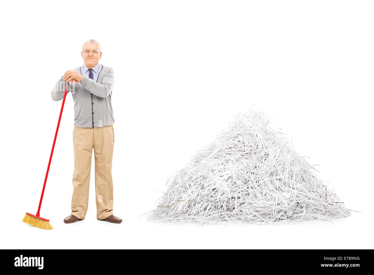 Senior in piedi da una pila di carta tagliuzzata con una scopa isolati su sfondo bianco Foto Stock