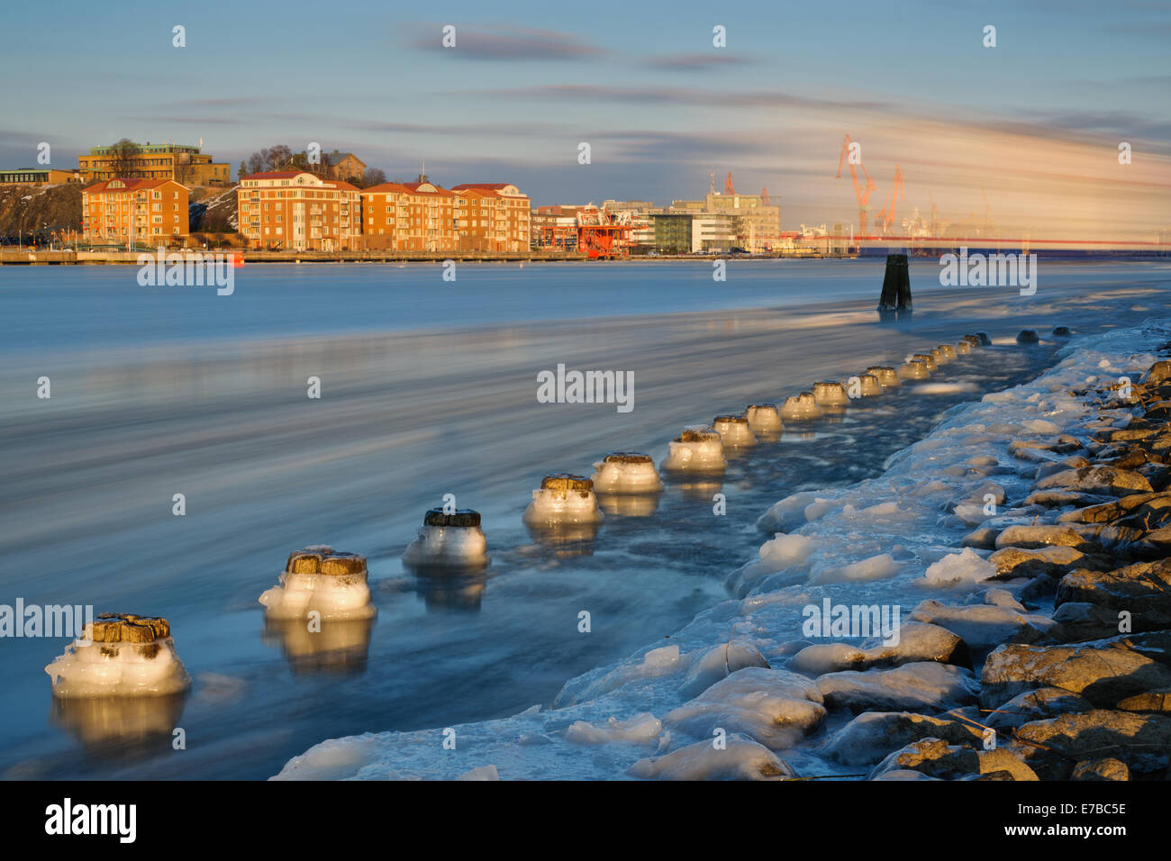 Acqua ghiacciata sul bordo di un fiume che scorre da una città Foto Stock