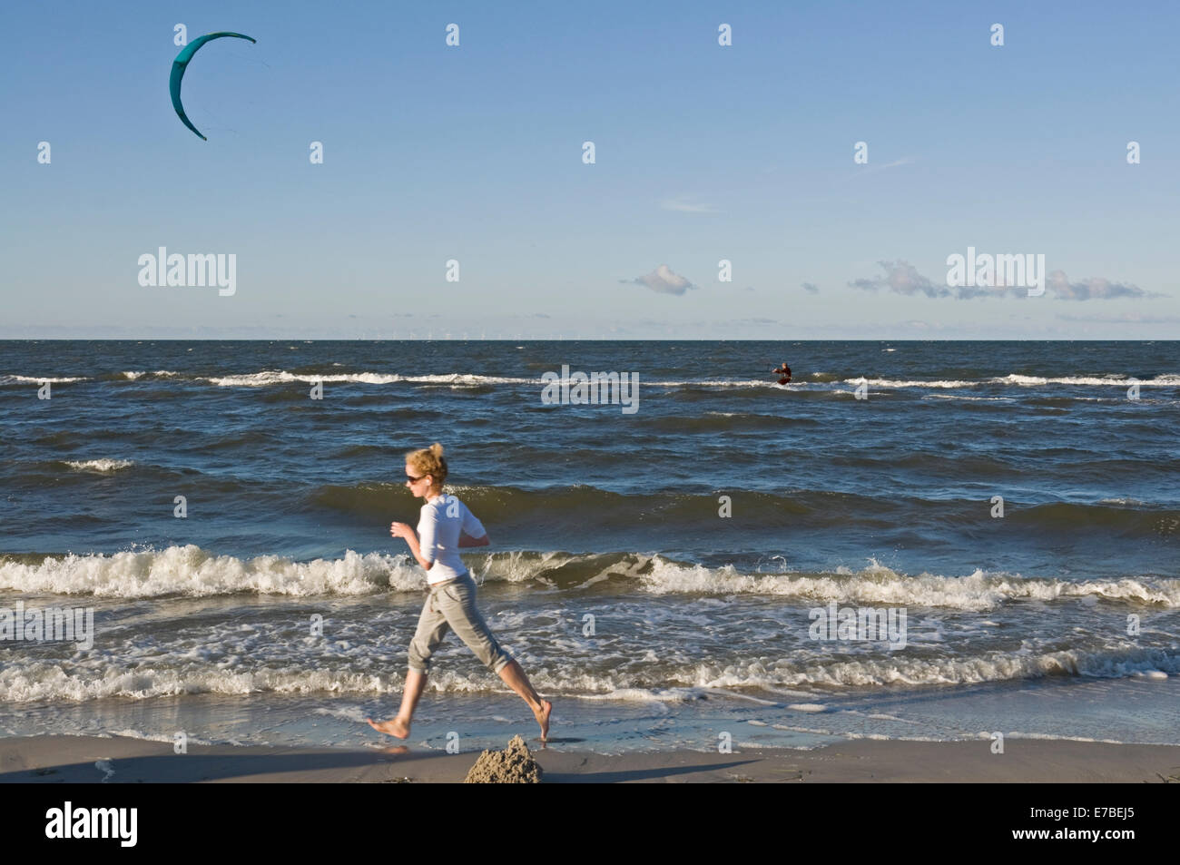 Donna jogging, uomo kite surfing sul mar Baltico a Prerow, Mecklenburg Vorpommern, Germania Foto Stock