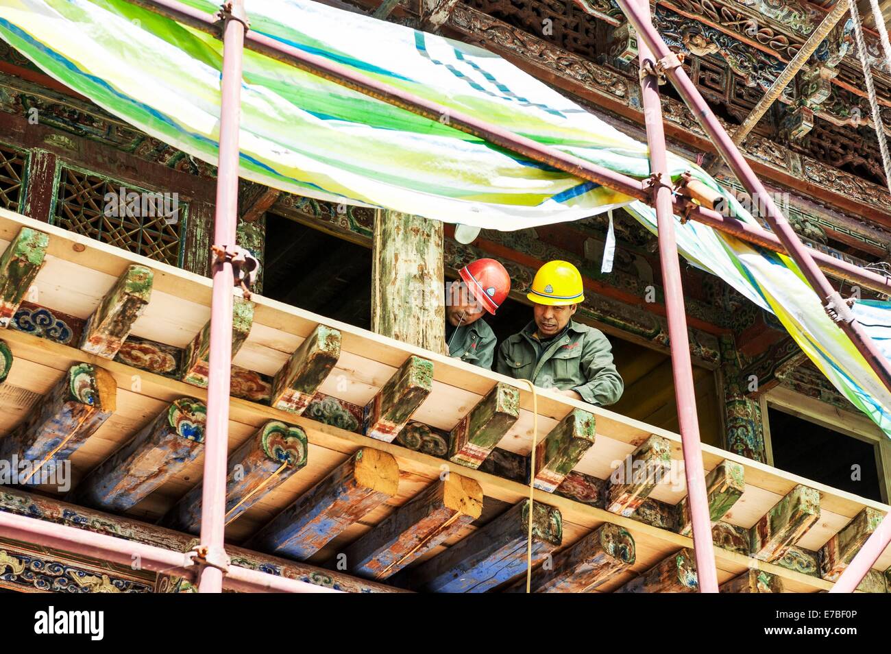 (140912) -- XIAHE, Sett. 12, 2014 (Xinhua) -- due lavoratori di riparazione di strutture in legno presso la residenza del primo Jamyang Shepa, fondatore del Monastero di Labrang, Xiahe nella contea di Gannan tibetano prefettura autonoma nel nord-ovest della Cina di Provincia di Gansu, Sett. 2, 2014. Il monastero di Labrang, uno dei più importanti del buddismo tibetano monastero in Cina sta subendo il più grande programma di rinnovamento sin dalla sua istituzione nel 1709. I lavori di ristrutturazione, che ha avuto inizio nel mese di aprile 2013, è destinato a sostituire la pietra e strutture in legno all'interno del monastero che era stato consumato dall'anni. Il monastero di Labrang remai Foto Stock