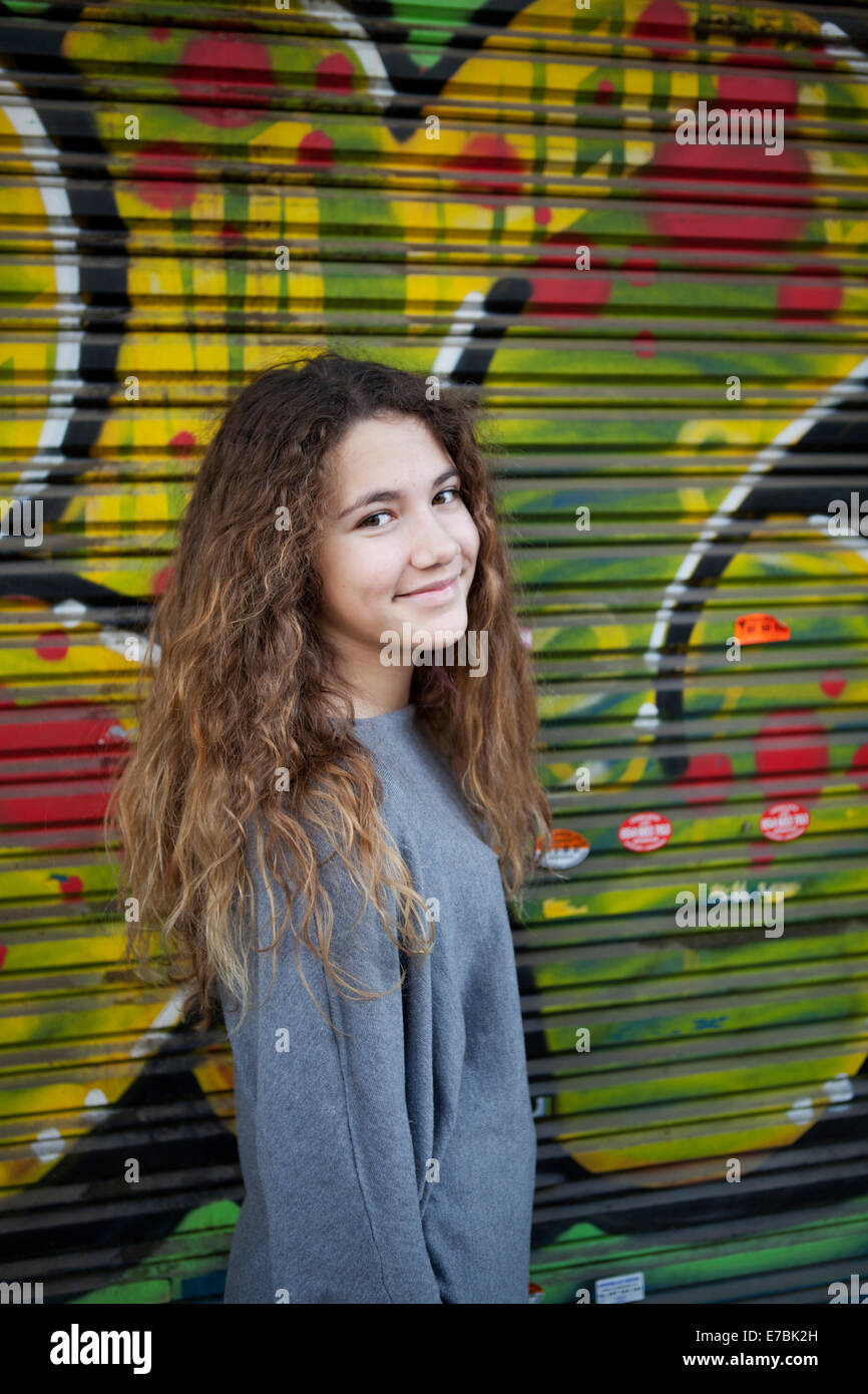 Ragazza adolescente di fronte a una coperta di graffiti vetrina Foto Stock