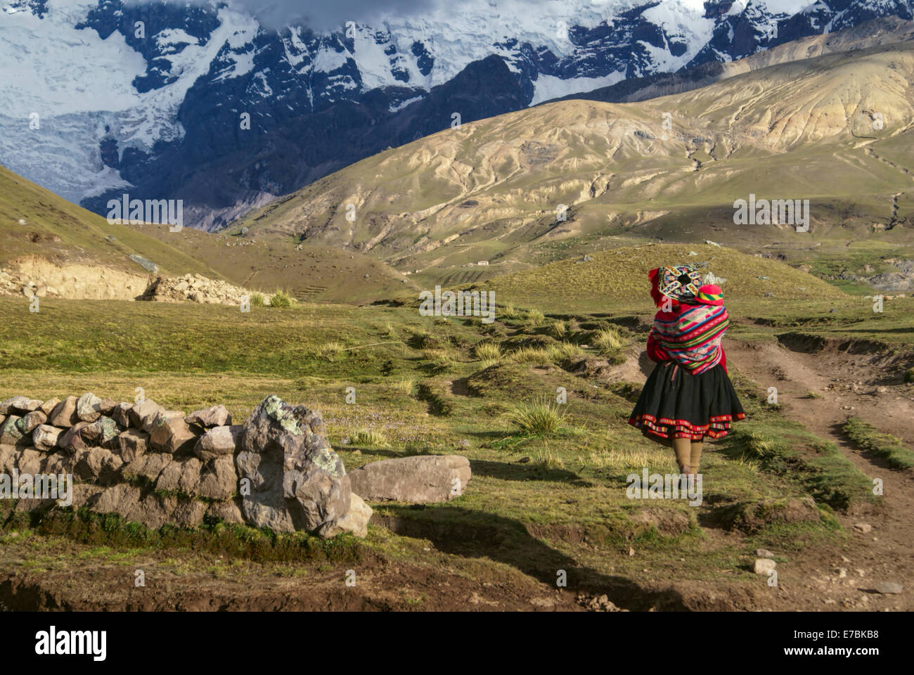 Una donna peruviana a piedi con un bambino sulla schiena in Sud Americana Andes Foto Stock