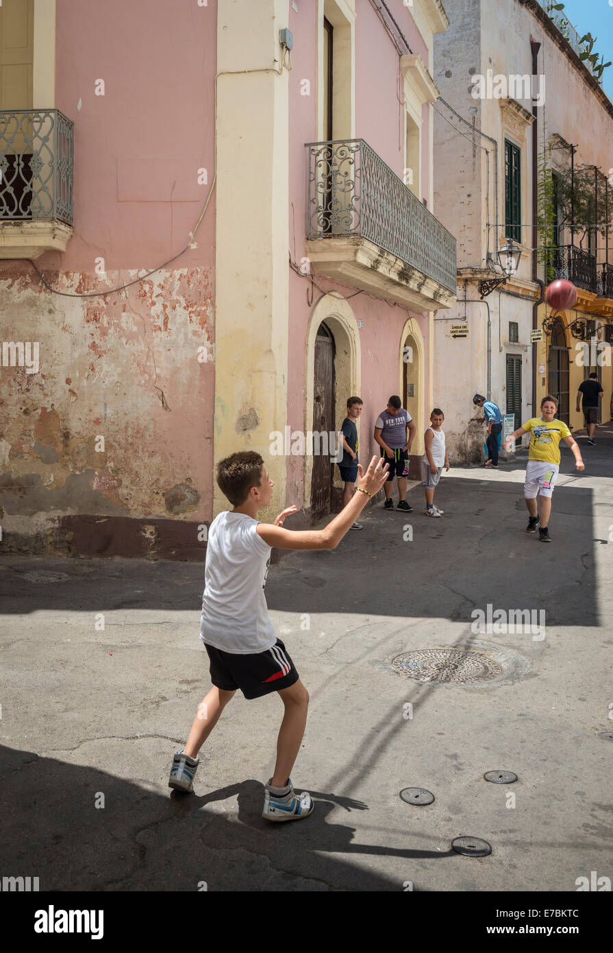 Bambini che giocano a calcio per strada nella vecchia città di pescatori di Gallipoli, Puglia, Italia meridionale. Foto Stock