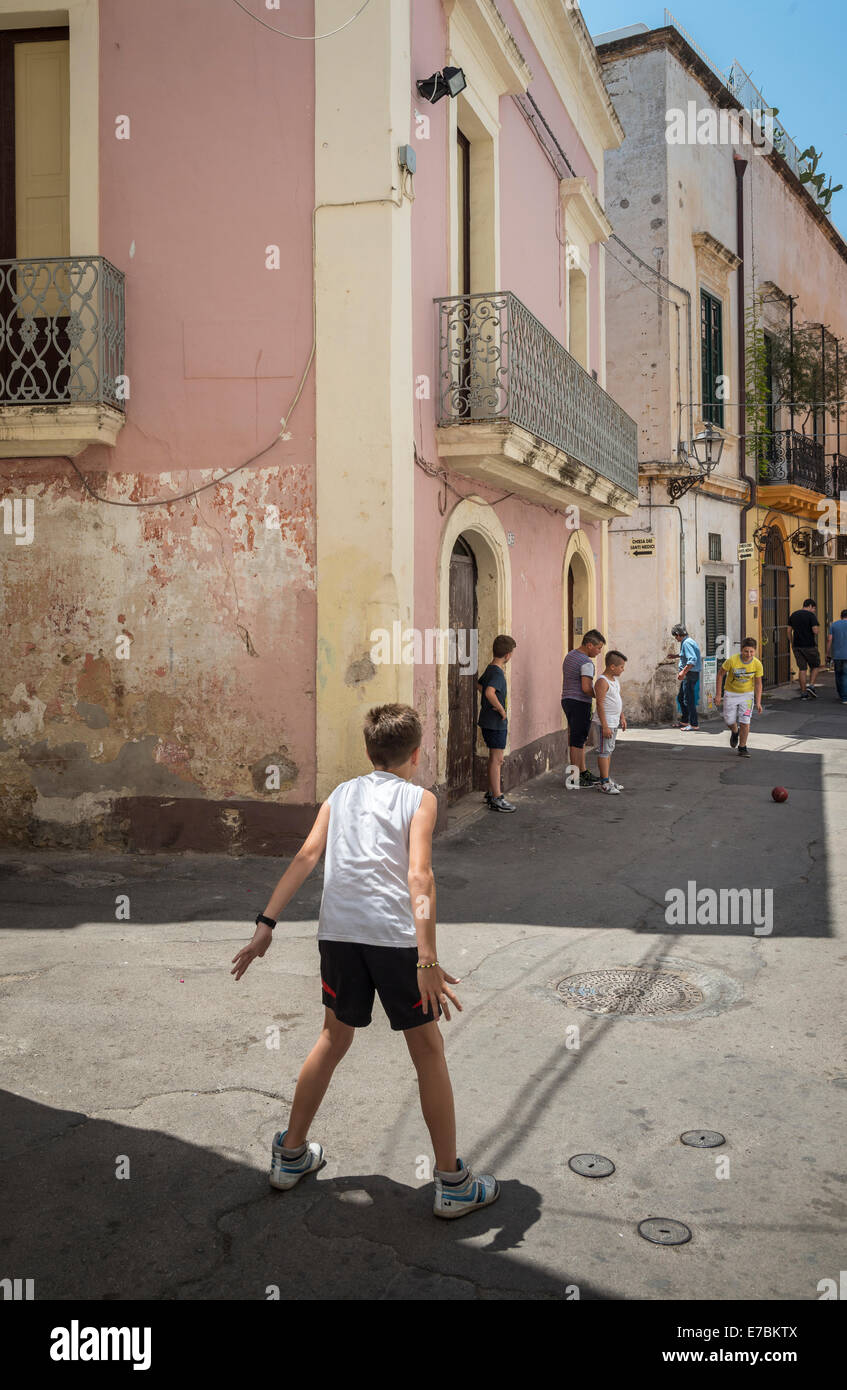 Bambini che giocano a calcio per strada nella vecchia città di pescatori di Gallipoli, Puglia, Italia meridionale. Foto Stock