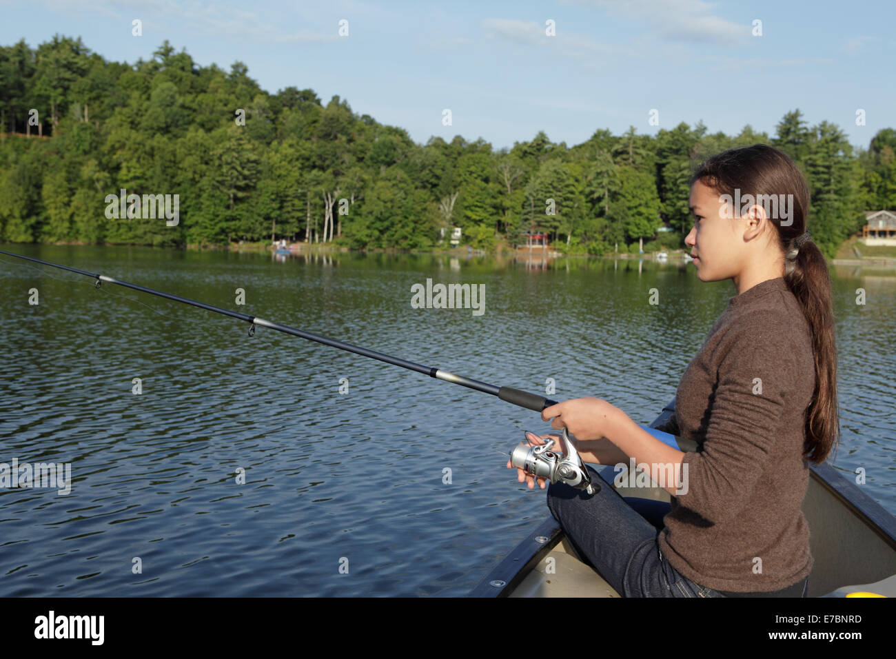 Ragazza giovane la pesca da una canoa Foto Stock