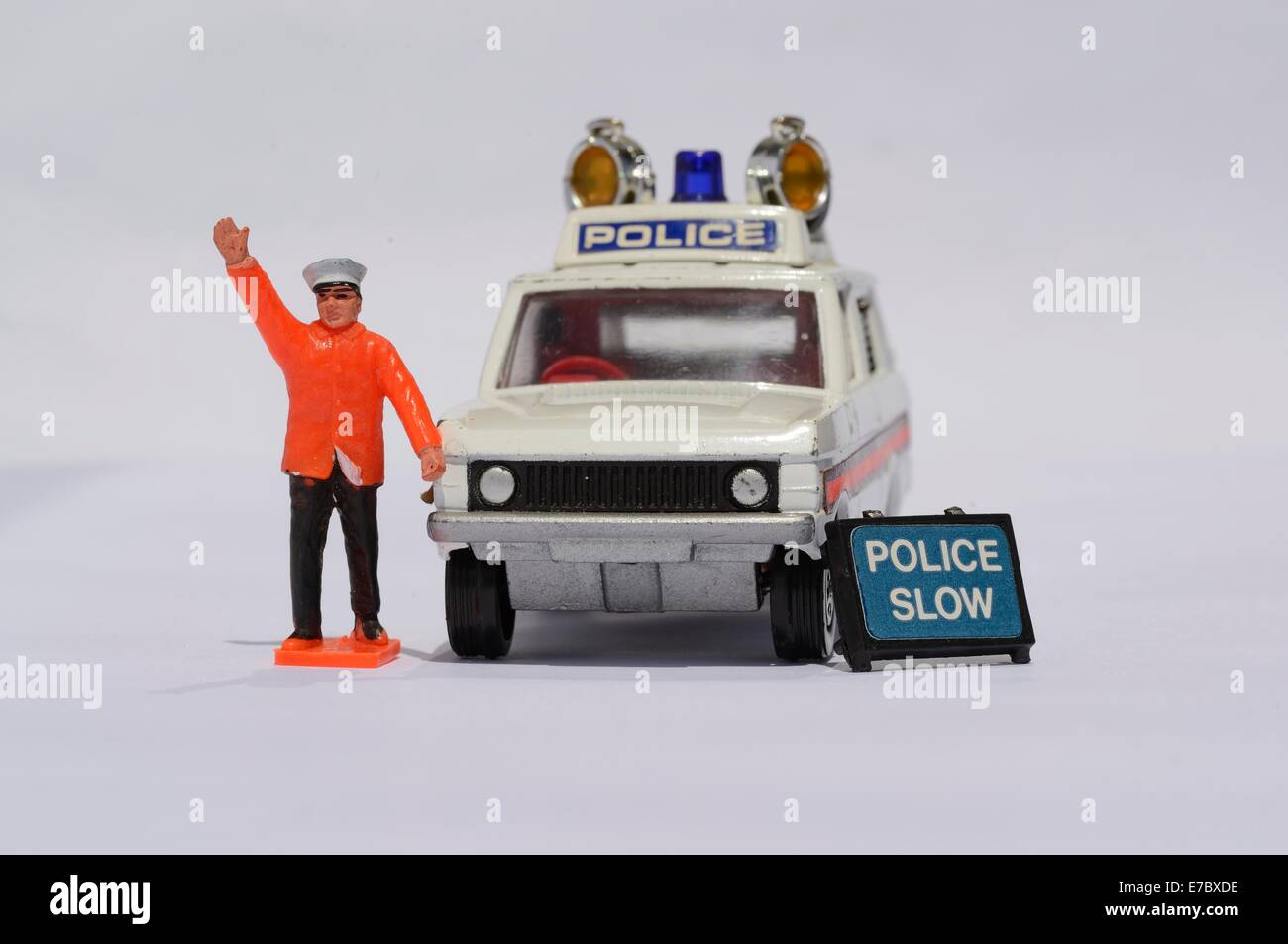 Un poliziotto giocattolo si alza con il braccio sollevato accanto a una Range Rover di polizia di Corgi Toys con un cartello accanto ad essa Foto Stock