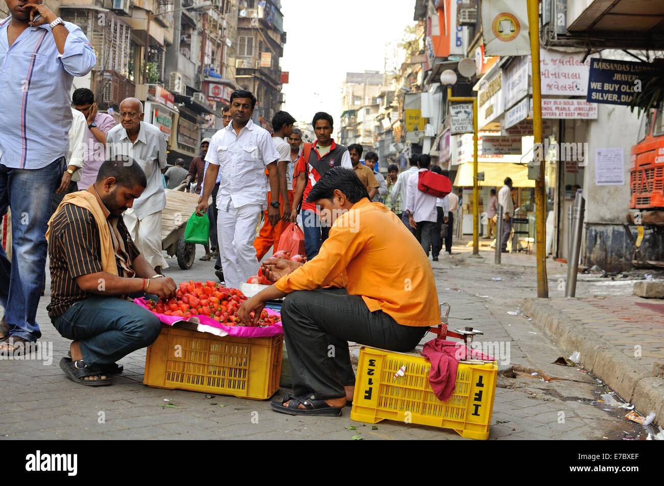 Gli uomini vende fragole sit dal loro piccolo box su una strada vicino al mercato di Mumbai Foto Stock