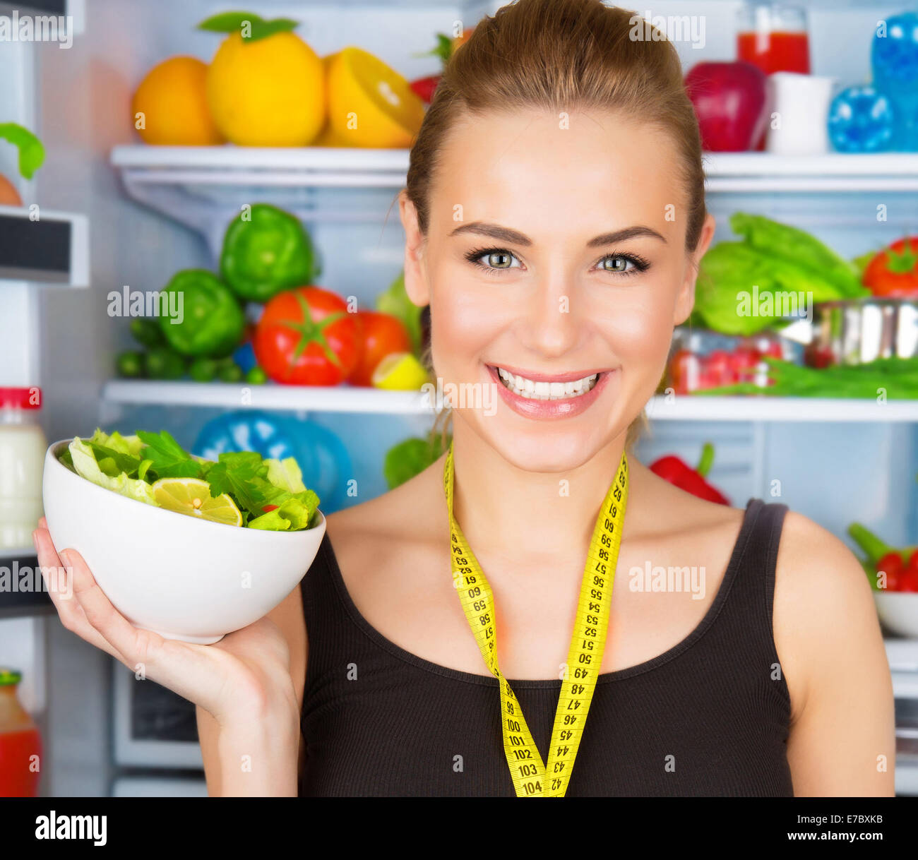 Closeup ritratto di carino donna sorridente con il metro a nastro e verdura fresca insalata, allenatore sportivo, cibo organico concetto Foto Stock