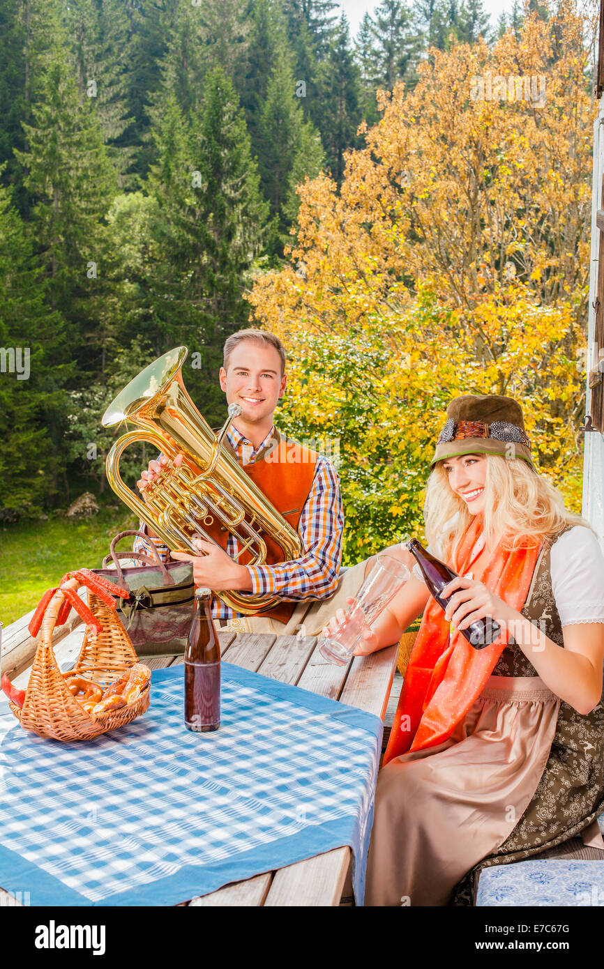 Coppia giovane nel tradizionale costume bavarese al partito su un pascolo estivo in montagna Foto Stock