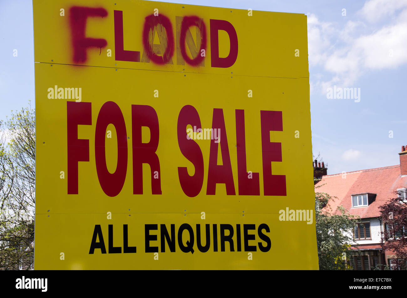 In vendita segno sul terreno accanto a un fiume che inondazioni in una zona residenziale. Foto Stock