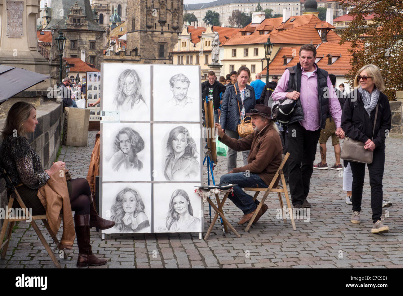 L'artista di strada al lavoro sul Ponte Carlo a Praga con passaggio di turisti Foto Stock