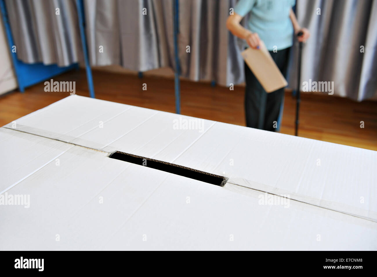 Dettaglio con un urna e una vecchia persona in canna da zucchero proveniente dalla cabina di voto in background Foto Stock