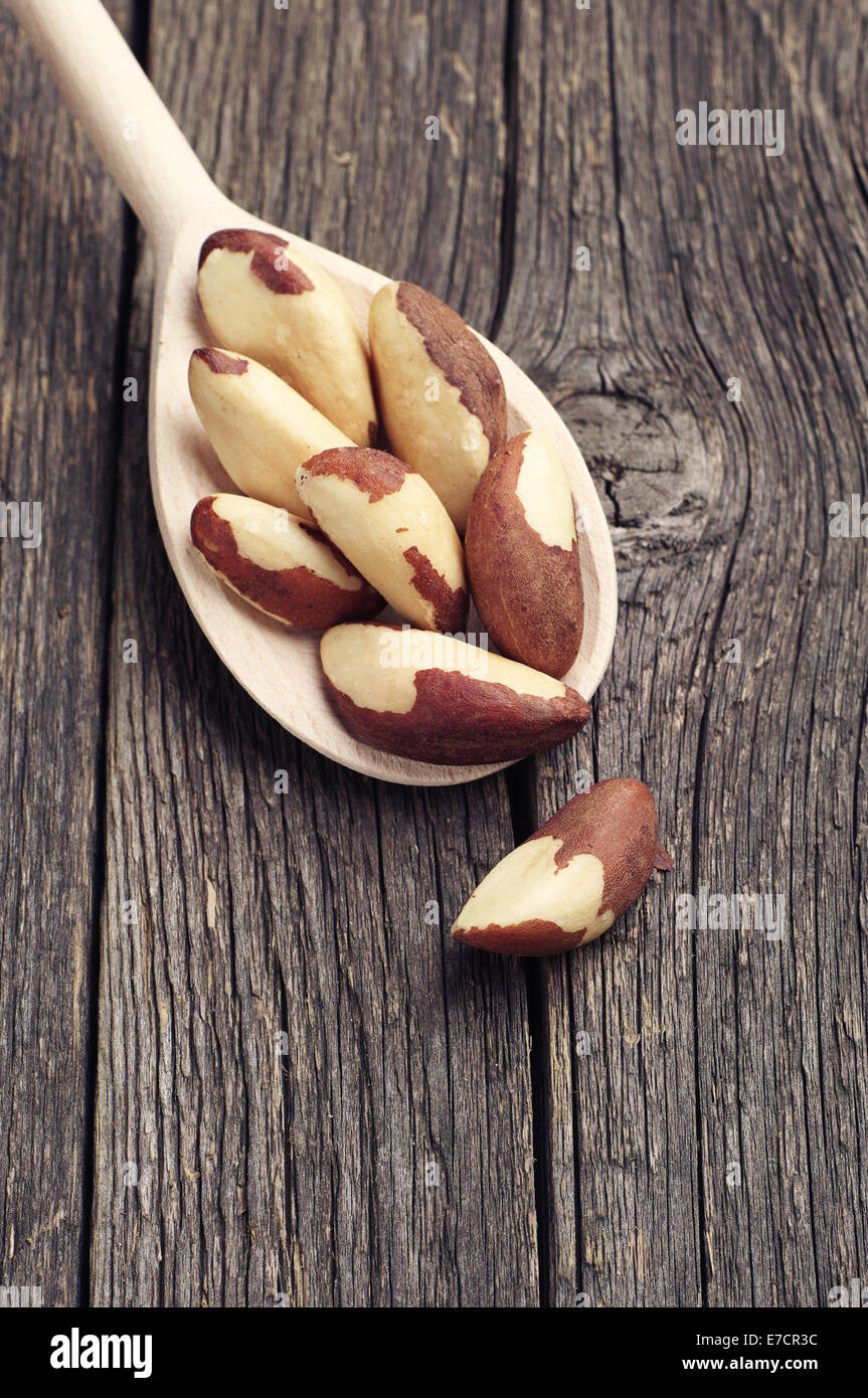 Le noci del Brasile in cucchiaio sull'annata sullo sfondo di legno Foto Stock
