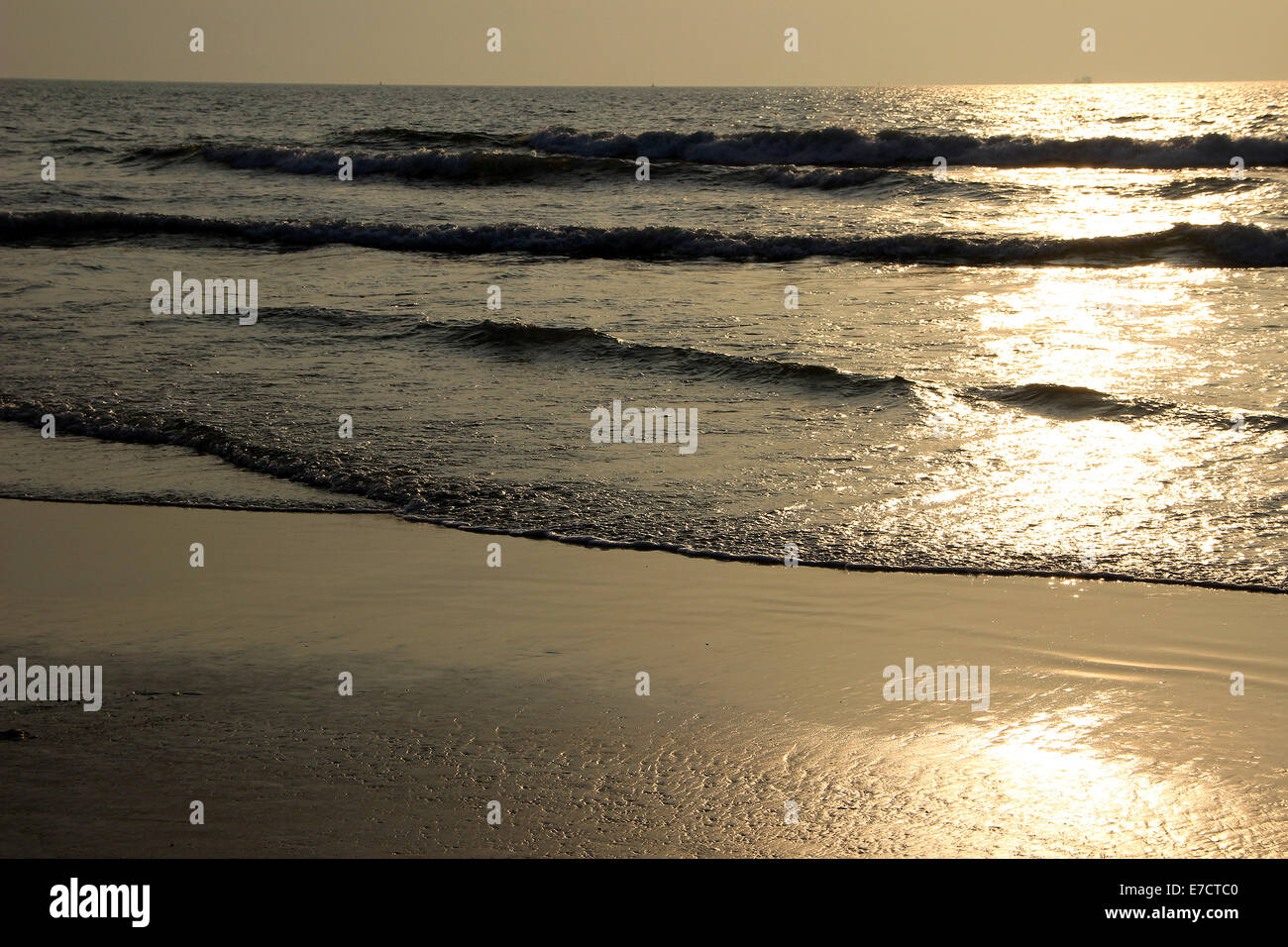 Calma le onde impostazione riflettente sun presso la spiaggia di Mangalore, Karnataka, India, Asia Foto Stock