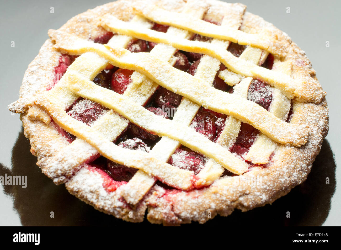 Torta di ciliegie con la parte superiore del reticolo su una piastra nera Foto Stock