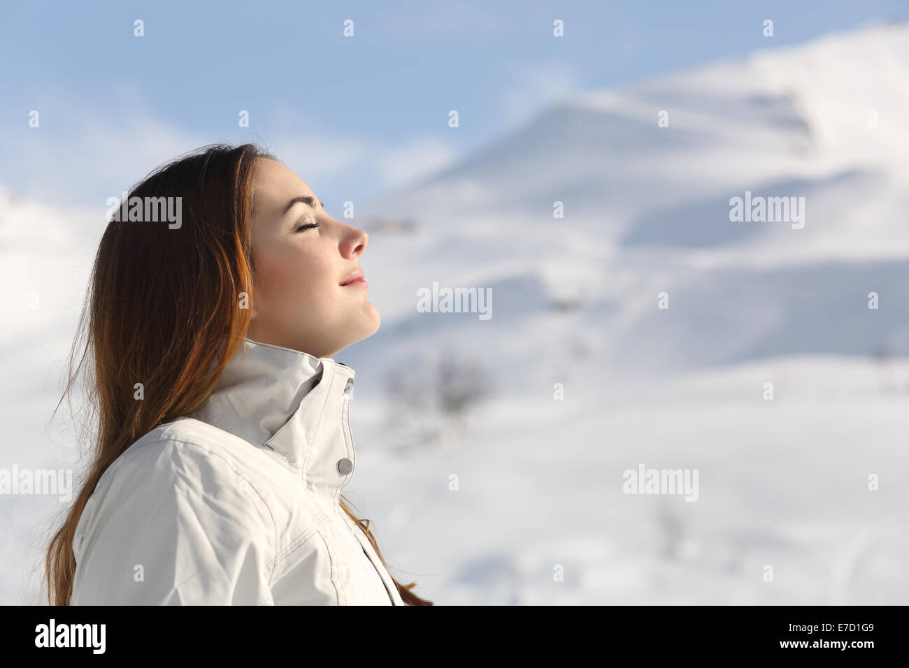 Profilo di un explorer donna respirando aria fresca in inverno con una montagna innevata in background Foto Stock