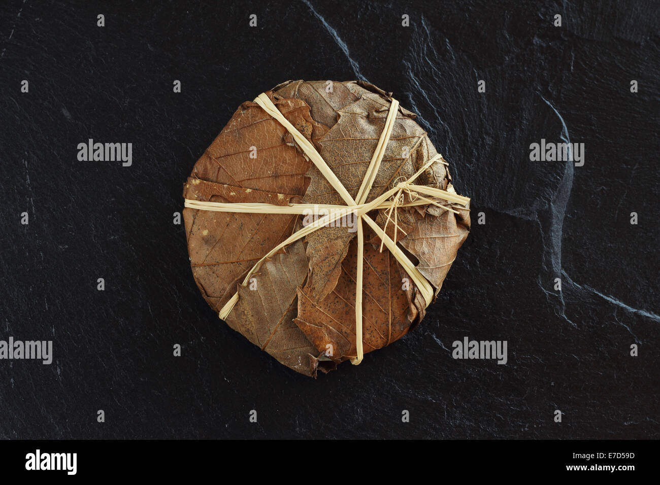 Formaggio di Banon avvolto con foglie di colore nero sulla lastra di pietra Foto Stock