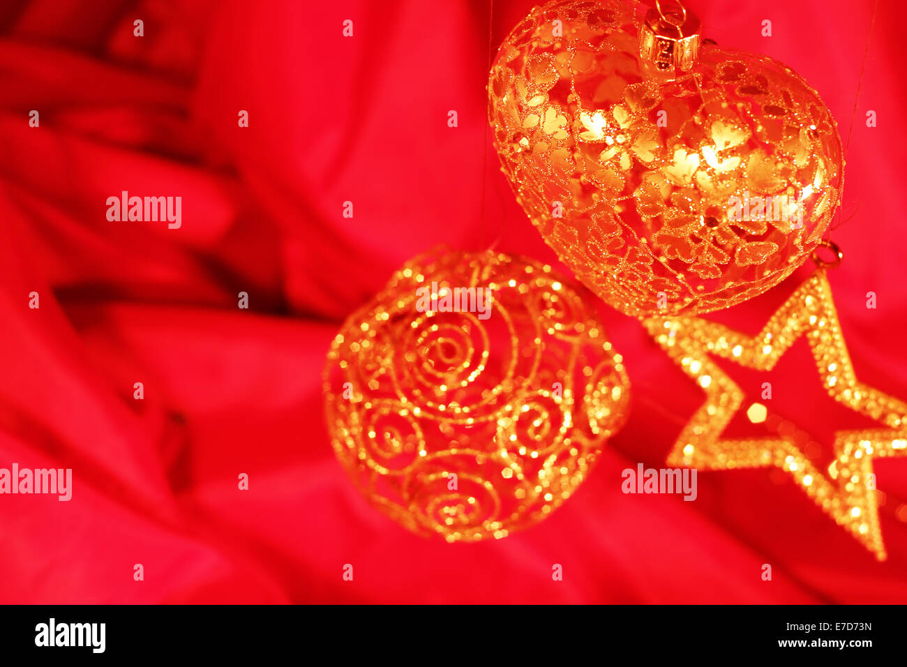 Golden decorazioni di Natale sulla stoffa rossa sullo sfondo Foto Stock