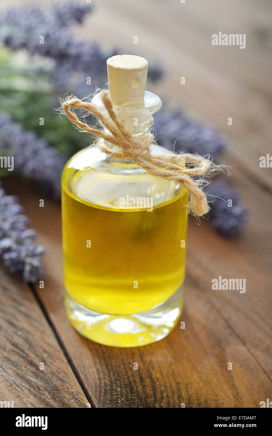 Essenziale di olio di lavanda con fiori freschi su sfondo di legno closeup Foto Stock