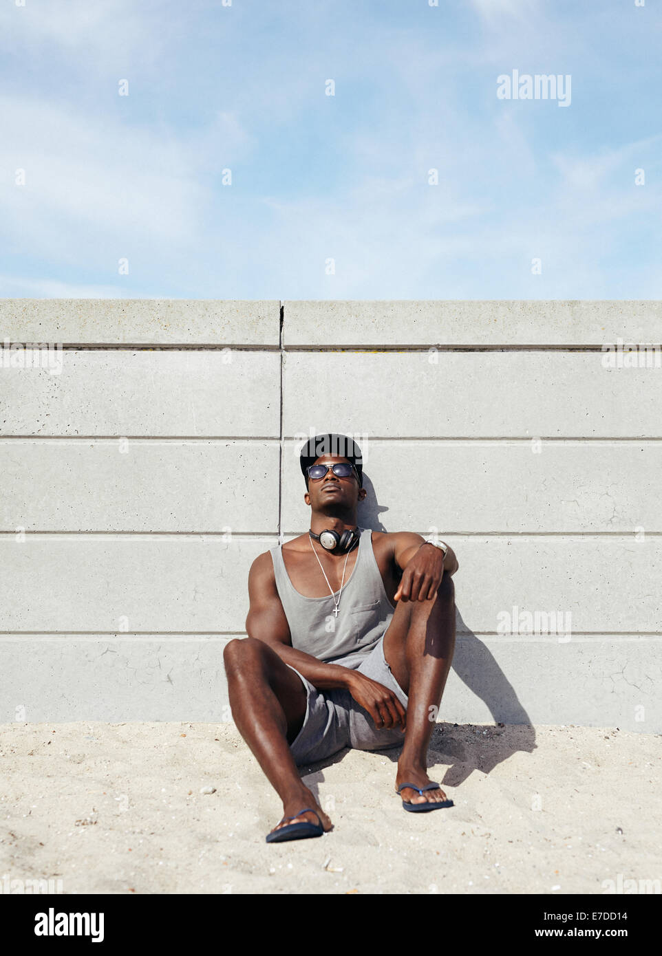 Muscoloso giovane rilassante sulla spiaggia. Uomo Africana appoggiata ad una parete seduta. Foto Stock