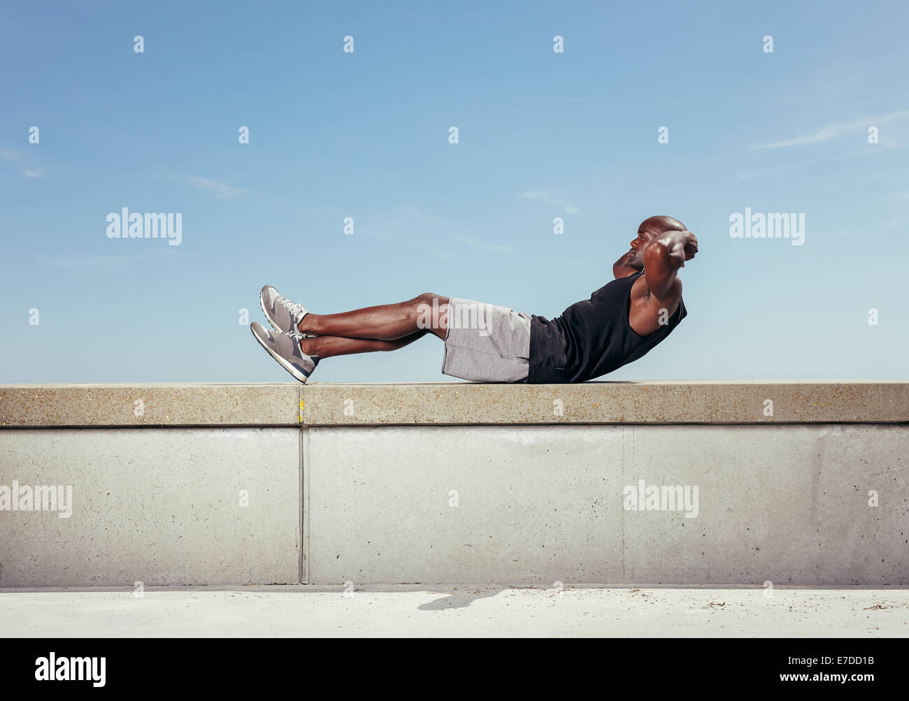 Atleta facendo sit ups contro sky. African maschio modello esercizio all aperto con copia spazio. Foto Stock