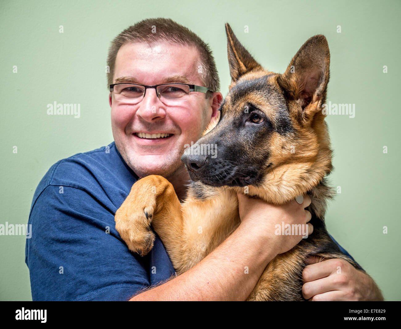 Felice giovane in posa con il suo pastore tedesco pet Foto Stock